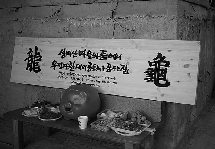 집 이름을 새긴 나무 현판과 상차림